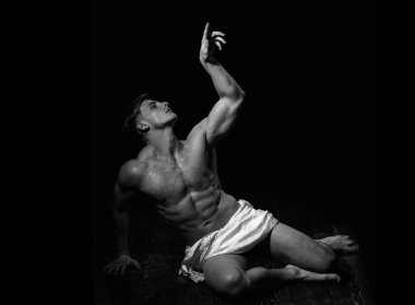 Kaslı, ıslak vücutlu bir adam. Sanatsal seksi erkek vücudu. Atletik vücut geliştirici heykel gibi poz verir.