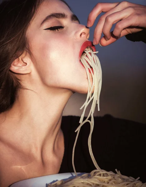 Чуттєва жінка їсть макарони. Голод, апетит, рецепт. Шеф-жінка з червоними губами їсть макарони. Італійські макарони або спагеті. Жінка з червоними губами їсть макарони.. — стокове фото