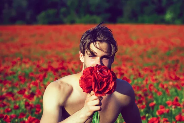 Sexy hombre joven desnudo celebrar ramo de flores de amapola roja. —  Fotos de Stock