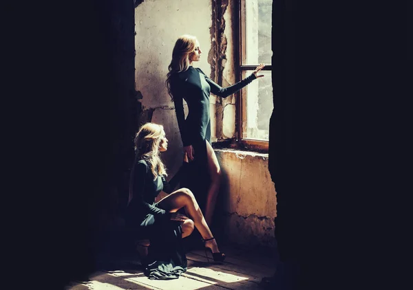 Vackra kvinnor i gröna klänningar nära gamla fönster. Retro mode modeller står nära vintage stenig vägg. — Stockfoto