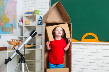 Astronot gibi giyinmiş, sınıfta oyuncak roketle oynayan, astronot olmayı hayal eden bir öğrenci. Çocukluk Geleceğin Rüyaları.