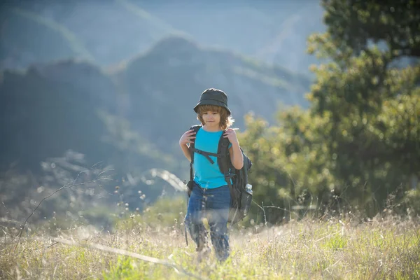 Sırt çantalı bir çocuk dağda yürüyüş yapıyor. Çocuk yerel bir turist yerel bir yürüyüşe çıkıyor.. — Stok fotoğraf