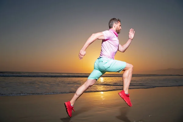 Mann läuft Jogger an. Junger Mann läuft am Strand des Meeres entlang bei einem fantastischen Sonnenuntergang. — Stockfoto