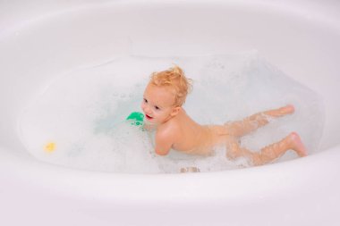 Sağlık ve günlük rutin bakım kavramı. Sevimli küçük çocuk köpük banyosuyla iyi eğlenceler. Banyodaki çocuk küvetli..