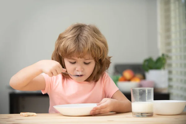 Retrato de un niño comiendo sopa o desayunando almorzando junto a la mesa en casa con cuchara. Alimentos saludables para niños. — Foto de Stock