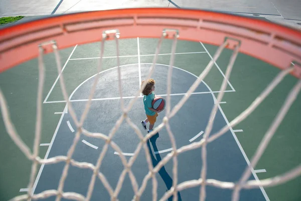 Glücklicher kleiner Junge spielt Basketball auf Spielplatz. — Stockfoto