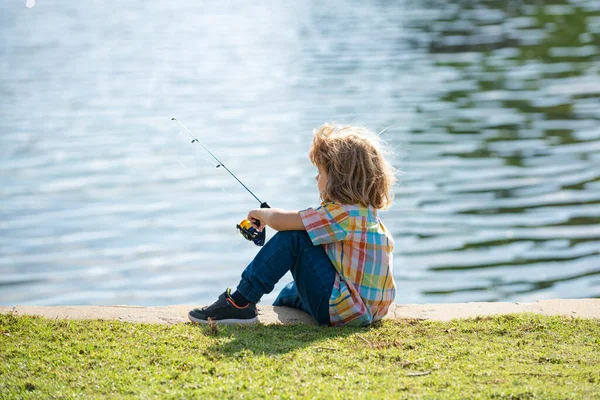 Un ragazzo pescatore. Ragazzo con la trottola al fiume. Ritratto di ragazzo eccitato pesca. Ragazzo al molo con asta. Concetto di pesca. — Foto Stock