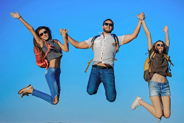 Gelukkige vrienden, toeristen springen op de top van de berg op de blauwe lucht. Zomervakantie. Reizen en wandelen. — Stockfoto