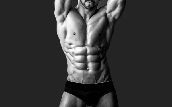 En naken manlig kropp i byxor som poserar med bara bröst på svart. Sexiga muskulösa män med naken överkropp. — Stockfoto