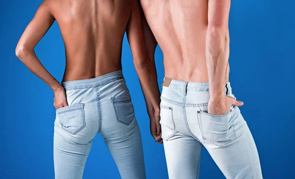 Couple en jeans, pantalon en denim vue de dos, couple sexy nu sur fond bleu. — Photo