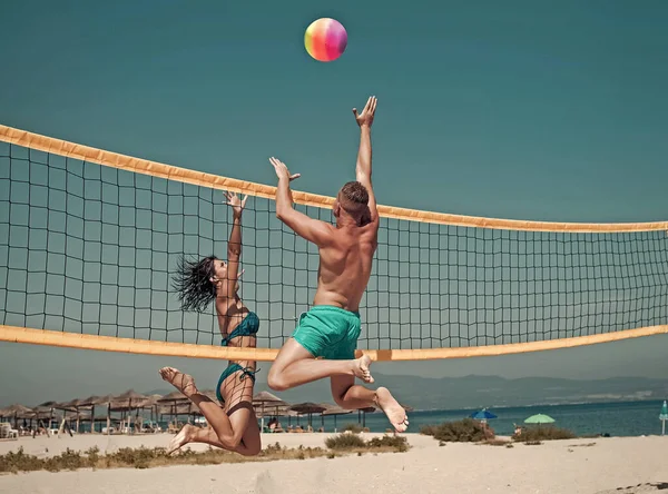 Couple have fun playing volleyball. Young sporty active couple beat off volley ball, play game on summer day.