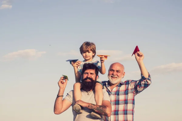 Joyeuse fête des pères. Heureux trois générations d'hommes s'amusent et sourient sur fond de ciel bleu. Grand-père jouant. Avion prêt à voler. — Photo