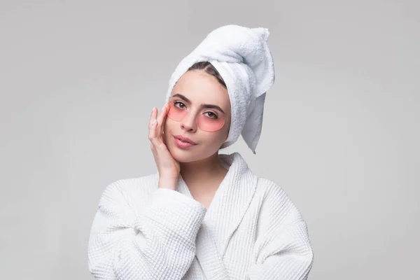 Femme appliquant des patchs oculaires. Gros plan fille portrait avec serviette sur la tête. Portrait de femme de beauté avec des patchs montrant un effet de peau parfaite. Masque yeux patchs cosmétiques femme visage gros plan. — Photo