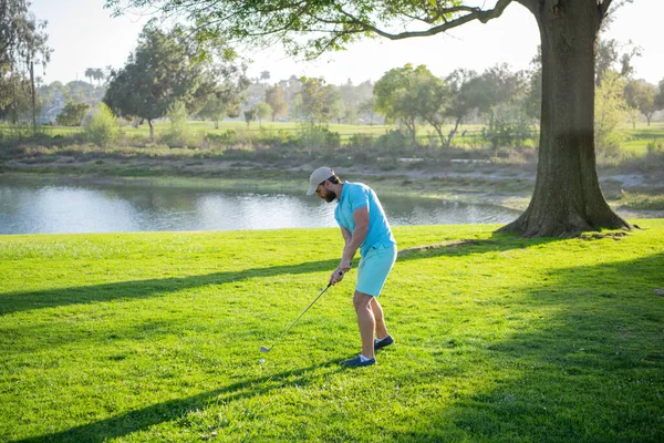 Golfista jugando al golf en el campo de golf por la noche. Golfista con palo de golf tomando un tiro. —  Fotos de Stock