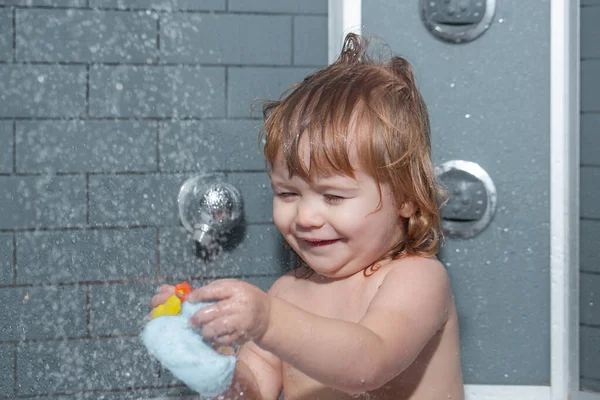 Kind baadt in een douche. Zwemmende baby. Gelukkig kind met zeepschuim op hoofd. — Stockfoto