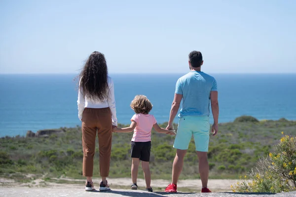 Happy family holidays. Joyful father, mother, baby son walk of sea sand beach. Active parents and people outdoor activity on summer vacations with children. Concept of healthy holiday and family