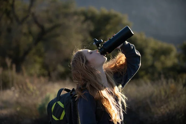 女性旅行者は水を飲む。山の中でリュックを持つ女性ハイカー。女の子のパノラマポイントで丘をハイキング。バックパッキング観光コンセプト — ストック写真