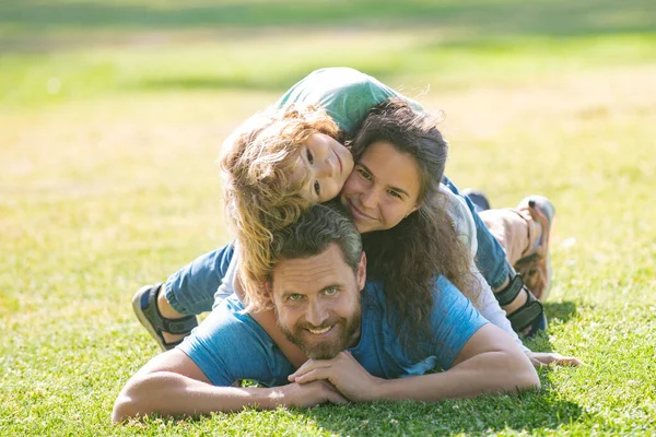 Glückliche junge Familie umarmt und umarmt zusammen draußen in der grünen Natur. — Stockfoto