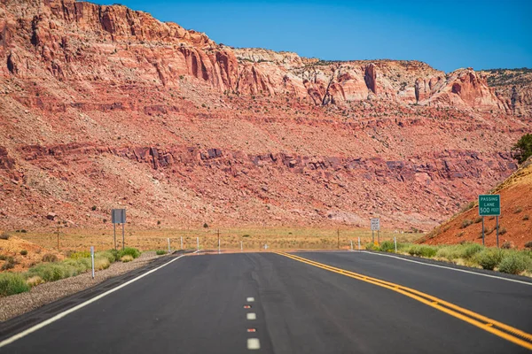 Τοπίο με πορτοκαλί βράχια, ουρανό με σύννεφα και ασφαλτοστρωμένο δρόμο το καλοκαίρι. Αμερικανικό οδικό ταξίδι. — Φωτογραφία Αρχείου
