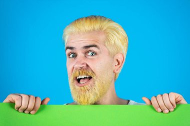 Adam boş bir kağıtla yüzünü kapatıyor. Mavi arkaplanda izole.