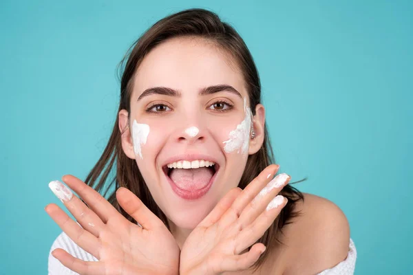 Funny beautiful young woman with clean fresh skin applying face cream. — Stock Photo, Image
