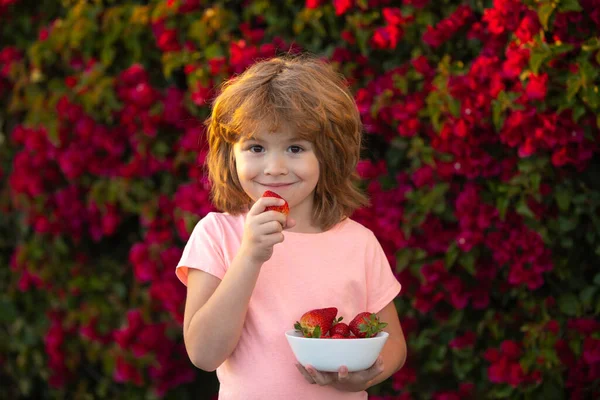 幸せな子供は夏の屋外でイチゴを食べる. — ストック写真