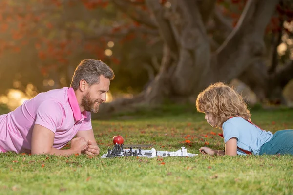 Happy family outdoor. Games and entertainment for children. Father and son playing chess in summer garden. — Stock Photo, Image