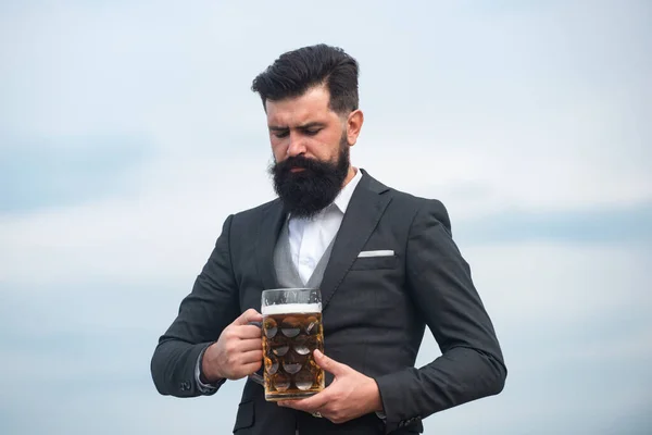 Man in classic suit drinking beer. Portrait of man with lifted high glass of beer. — Stock Photo, Image