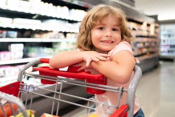 Парень с корзиной покупает еду в продуктовом магазине. Покупка товаров для детей в супермаркете. — стоковое фото