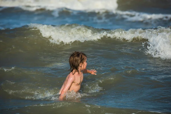 Niño jugando y divirtiéndose en la playa en el mar azul en verano. Niño feliz jugando en el mar. — Foto de Stock
