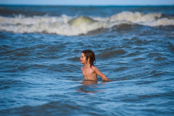 Niño nadando divirtiéndose y saltando en las olas del mar. Vacaciones en el mar para familia. — Foto de Stock