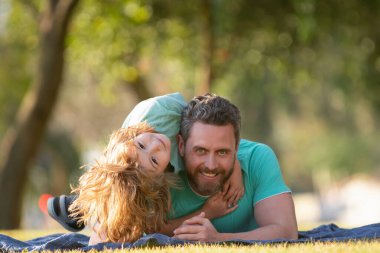 Baba oğul parkta doğaya sarılıp kucaklaşıyorlar. Mutlu baba ve çocuk güneşli bir parkta tatilin tadını çıkarıyorlar. Çocuklar ebeveynleri sever. Şefkat ve şefkat, sevgi dolu aile..
