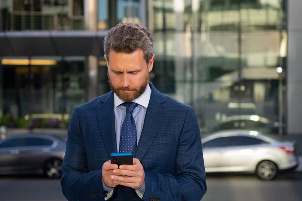 Porträt eines Geschäftsmannes, der in einem Büro steht. Geschäftsmann telefoniert. Porträt eines gut gelaunten Büroangestellten, der in der Nähe moderner Büros mit dem Handy telefoniert. — Stockfoto