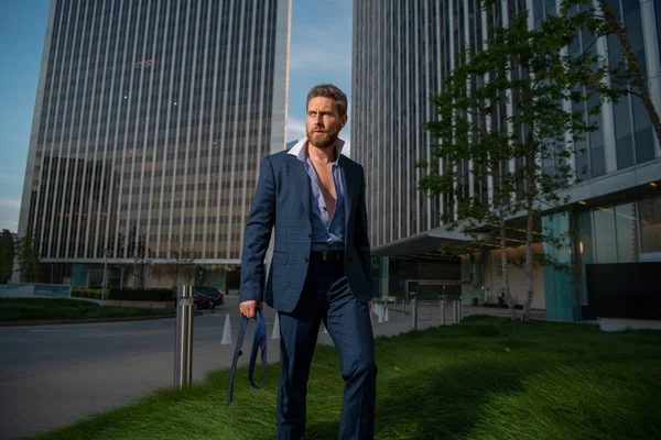 Homme d'affaires moderne en costume debout à l'extérieur avec paysage urbain en arrière-plan. — Photo