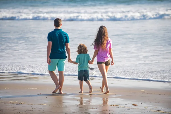 幸せな家族の休日。楽しい父、母、海の砂のビーチの赤ちゃんの息子の散歩。子供と夏休みに積極的な親や人々の屋外活動。ファミリーレジャー活動コンセプト. — ストック写真