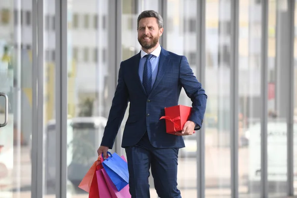 Επιχειρηματίας κρατώντας τσάντες για ψώνια και περπατώντας στο κατάστημα. Ψώνια και πληρωμή. Έννοια shopaholic ψώνια. — Φωτογραφία Αρχείου