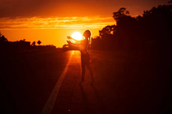 Silueta negra de chica bonita o mujer hermosa, modelo delgado sexy, con poses de pelo largo en la playa del mar al atardecer al aire libre sobre fondo de cielo amarillo — Foto de Stock