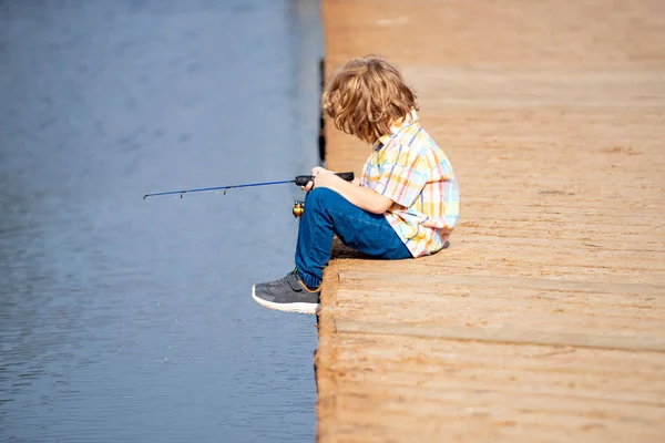 Concept de pêche. Pêche d'enfant sur le lac. Jeune pêcheur. Garçon avec fileuse à la rivière. Portrait de garçon excité pêche. Garçon à la jetée avec tige. — Photo