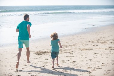 Baba ve oğul denizde koşuyor. Baba ve çocuk dışarıda eğleniyor..