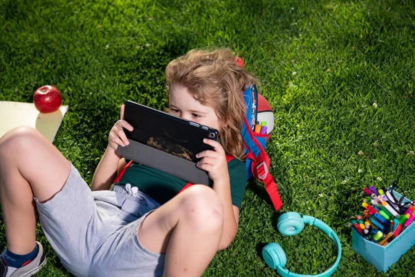 Liten barn lärande utomhus genom att studera på nätet och arbeta på surfplatta i grönt fält. Förskoleelev utomhus. — Stockfoto