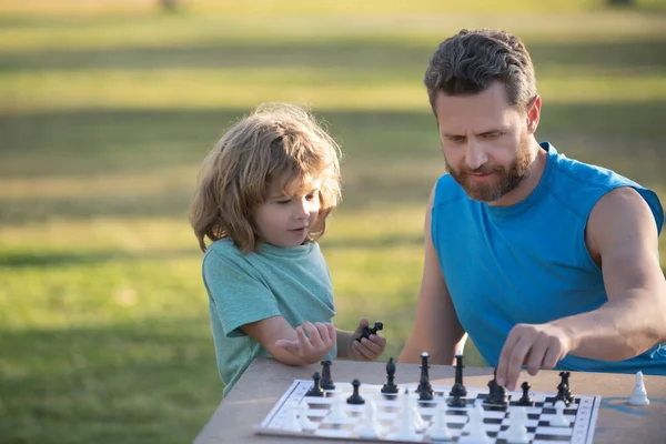 Father play chess with son. Family outside game. Games and activities for children.