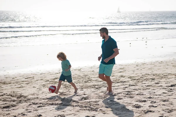 父と息子は夏休みにビーチでサッカーやサッカーをします。屋外で遊んでいる父と子供. — ストック写真