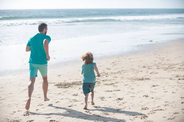父と息子は海を走っている。屋外で楽しむお父さんと子供. — ストック写真