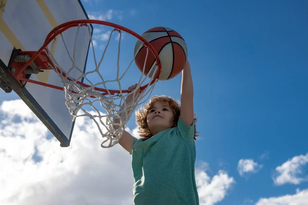 Basket barn spel. Söt liten pojke håller en korg boll försöker göra en poäng, utomhus på lekplatsen. — Stockfoto