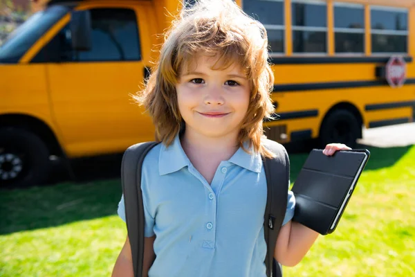 Portrait of happy little schoolboy pupil outdoor on school bus.