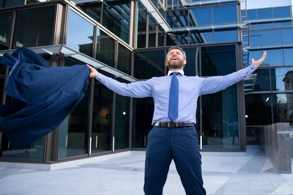 Business excitement. Business man keeping arms raised and expressing positivity outdoors. Businessman jumping for joy celebrating a successful.