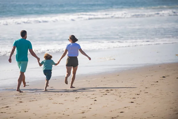 Famiglia felice che corre sulla spiaggia al tramonto. Concetto di famiglia itinerante. Persone sane. — Foto Stock