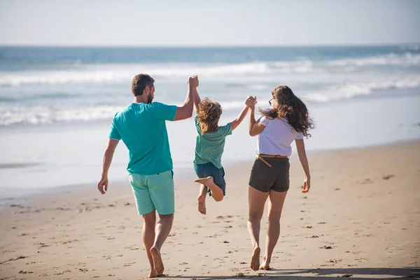 幸せな家族の休日。楽しい父、母、海の砂のビーチの赤ちゃんの息子の散歩。子供と夏休みに積極的な親や人々の屋外活動。フレンドリーな家族休暇の概念. — ストック写真