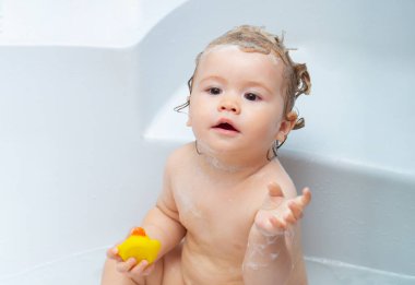 Köpükle oynayan sevimli çocuk. Tatlı erkek bebek banyoda banyo yapıyor ve banyo yapıyor..