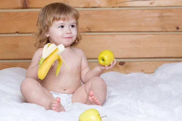 新鮮な果物を持つ子供。幸せな幼児はリンゴとバナナを食べる。子供の栄養. — ストック写真